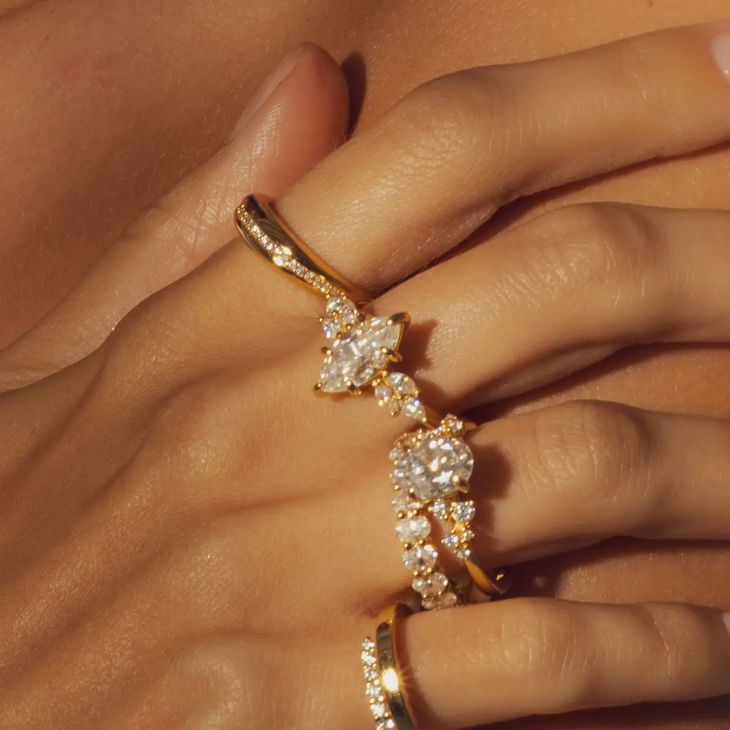 Perfil del anillo de compromiso con gema central marquesa y diamantes secundarios en configuración floral sobre banda de oro amarillo