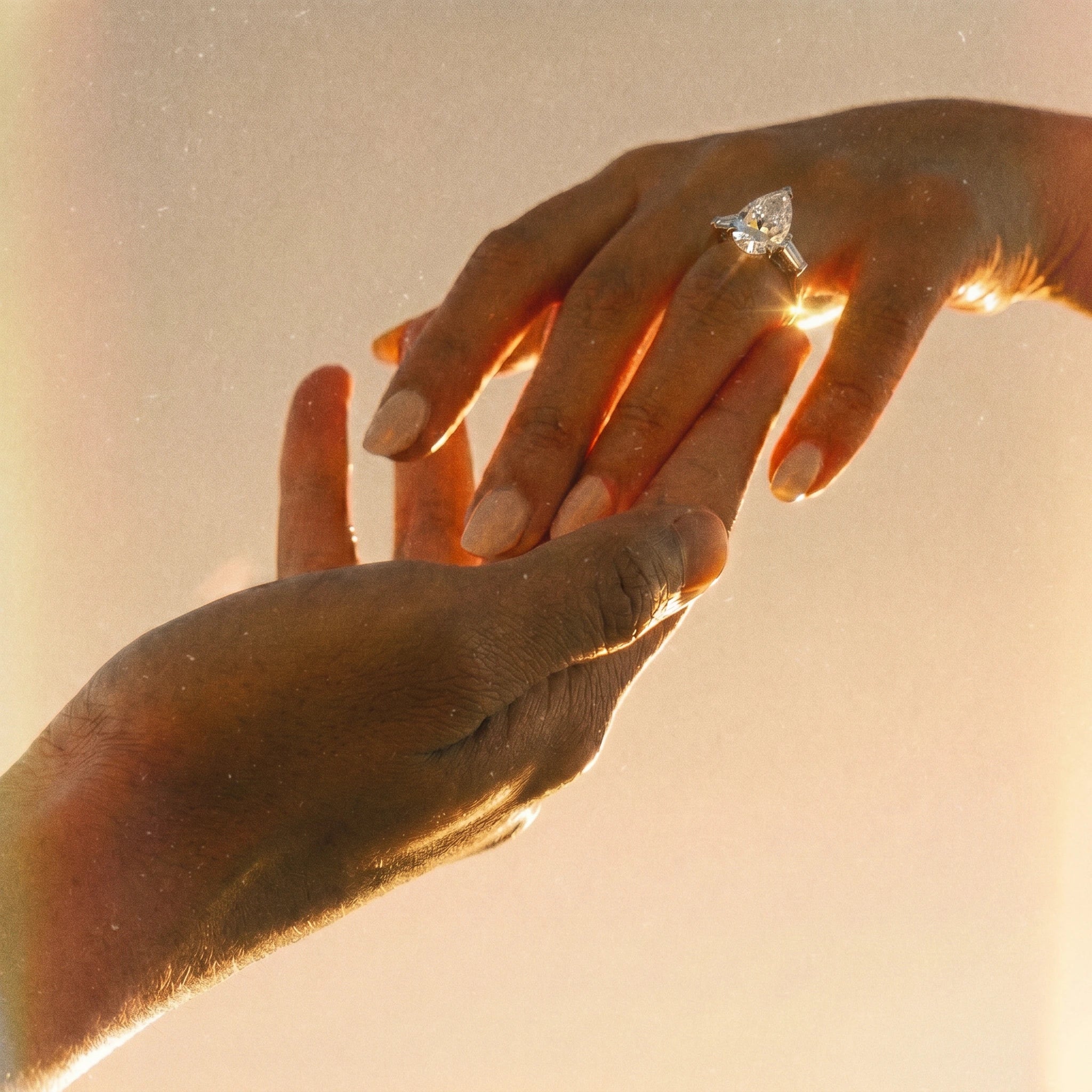 Anillo de compromiso corte pera sobre mano entrelazada en fotografía lifestyle a contraluz