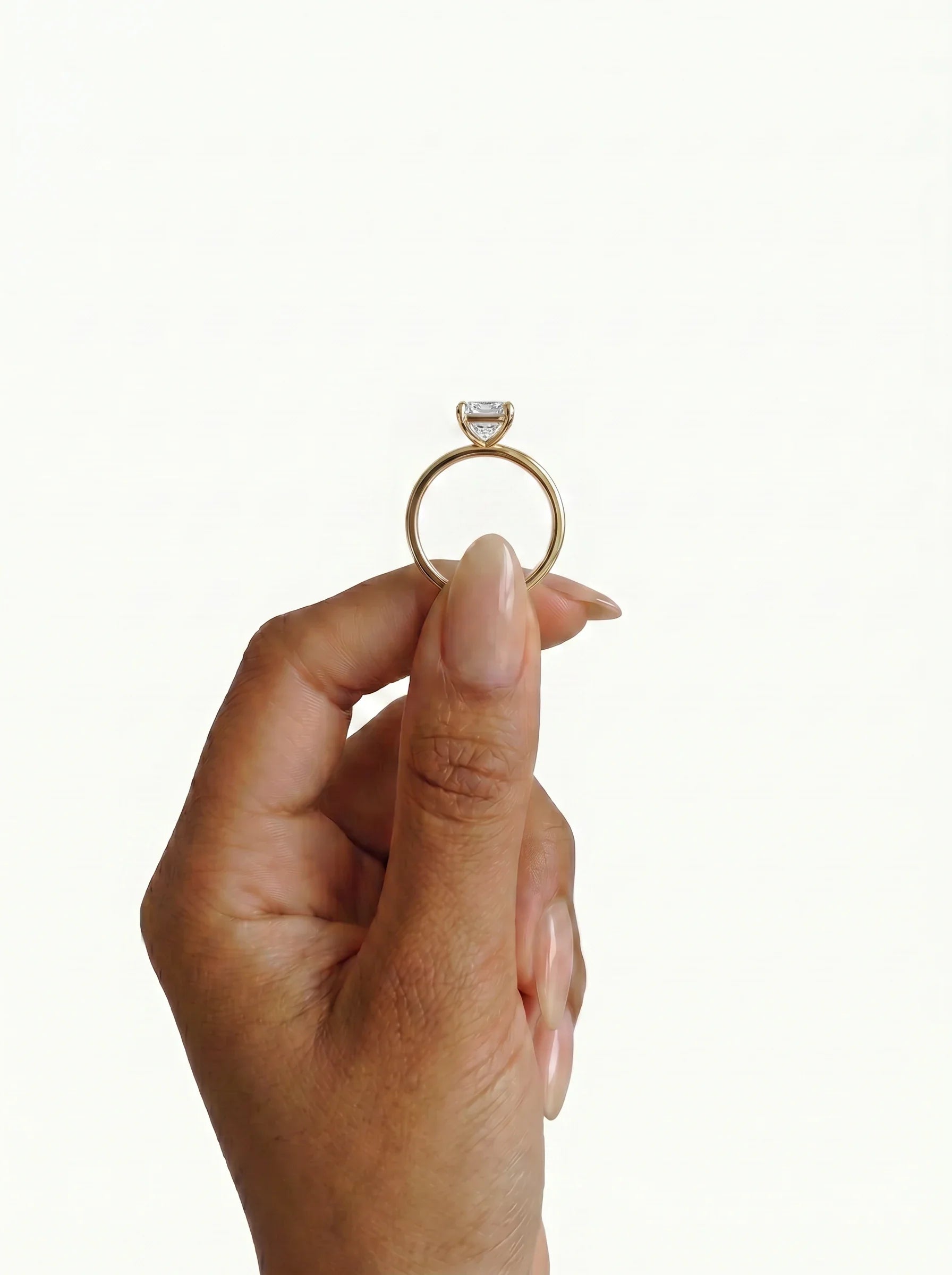 Anillo de compromiso GAIA radiante solitario en oro amarillo 18k de perfil entre los dedos