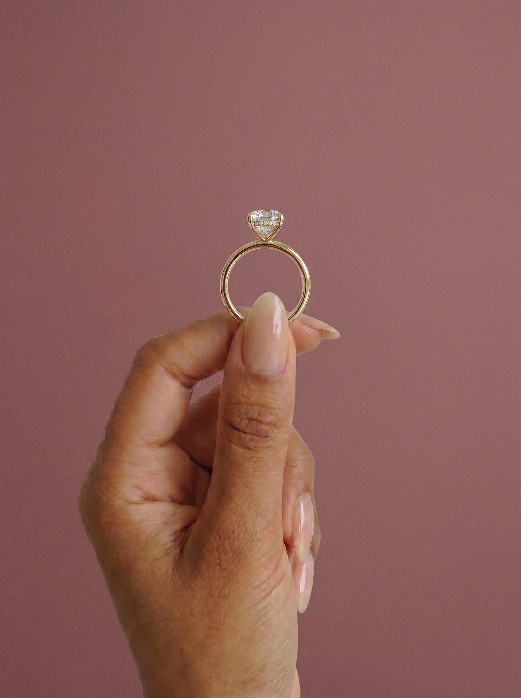 Anillo de compromiso solitario halo escondido THEIA oval en oro amarillo, detalle sujeto con pinza