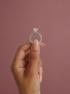 Anillo de compromiso solitario halo escondido THEIA oval en oro blanco, detalle sujeto con pinza