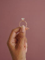 Anillo de compromiso solitario halo escondido THEIA oval en oro rosa, detalle sujeto con pinza